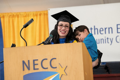 NECC student speaker, Iseline Mendoza, and son on stage at 2022 commencement event. 